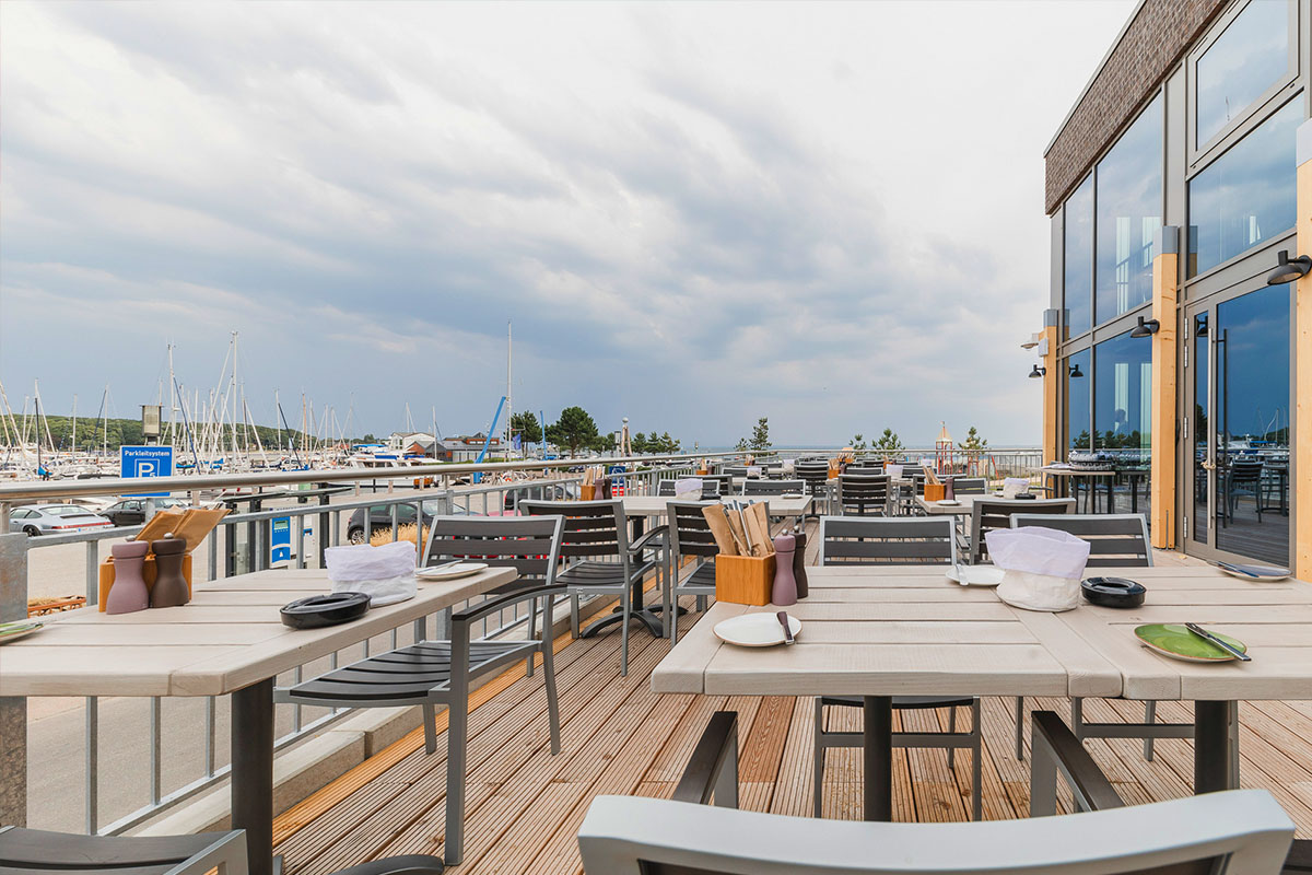 Außenbereich mit Tischen und Stühlen im arborea Marina Resort Neustadt in der Lübecker Bucht.