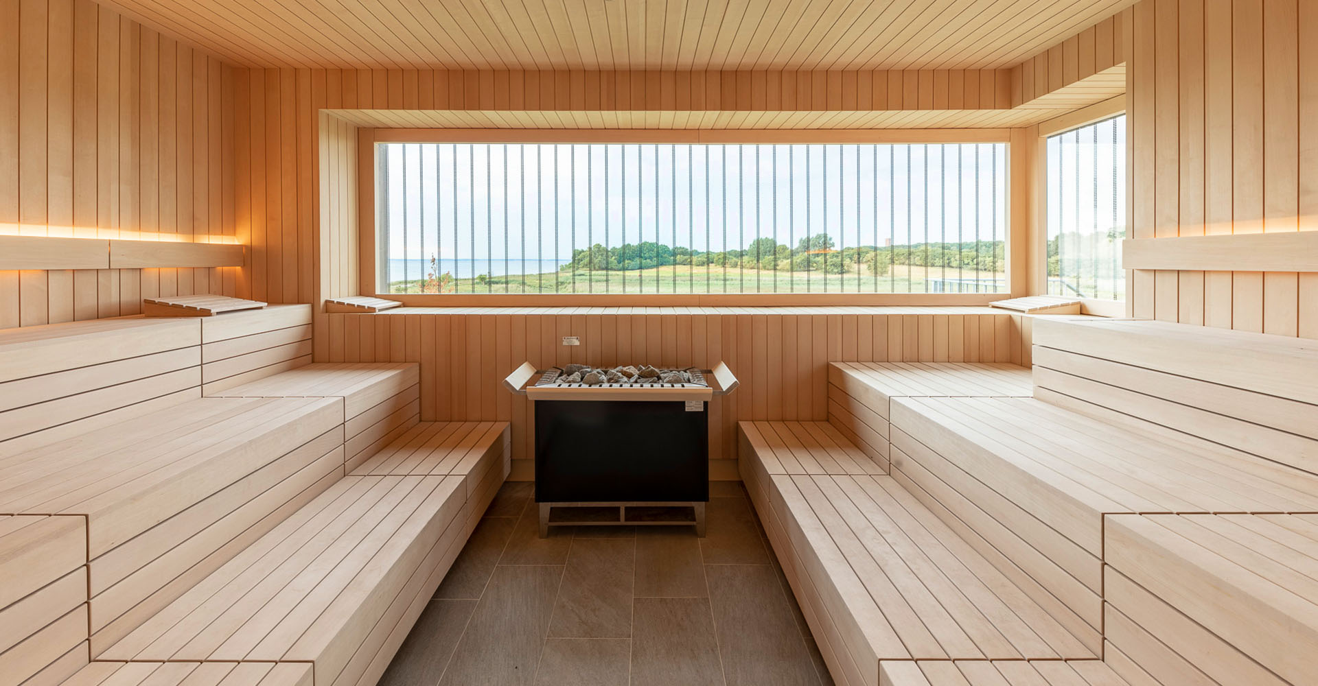 Hölzerne 90°C Panoramasauna an der Ostsee mit Blick auf friedliche grasende Rinder im SPARADISE des arborea Marina Resort Neustadt.