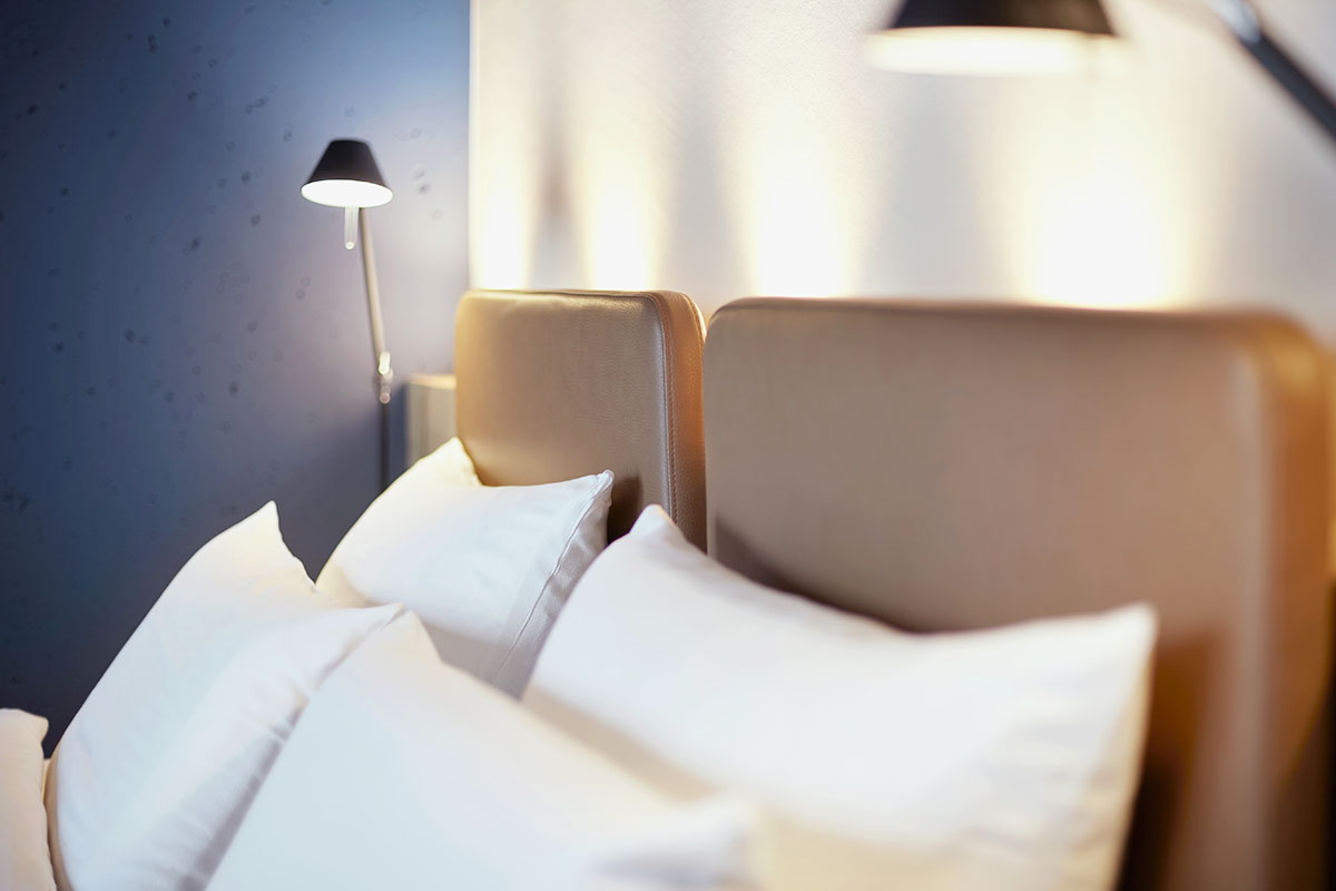 Kopfende mit gemütlichen Kissen des Kingsize Doppelbettes im Viererzimmer Auszeit des arborea Marina Resort Neustadt.