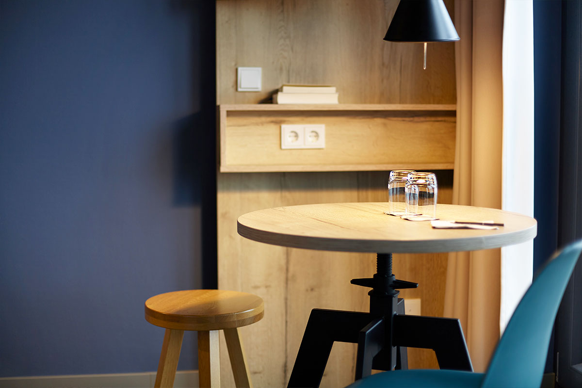 Detailaufnahme des kleinen, runden Esstisches mit zwei Stühlen und Gläsern im Doppelzimmer Ostsee im arborea Marina Resort Neustadt.