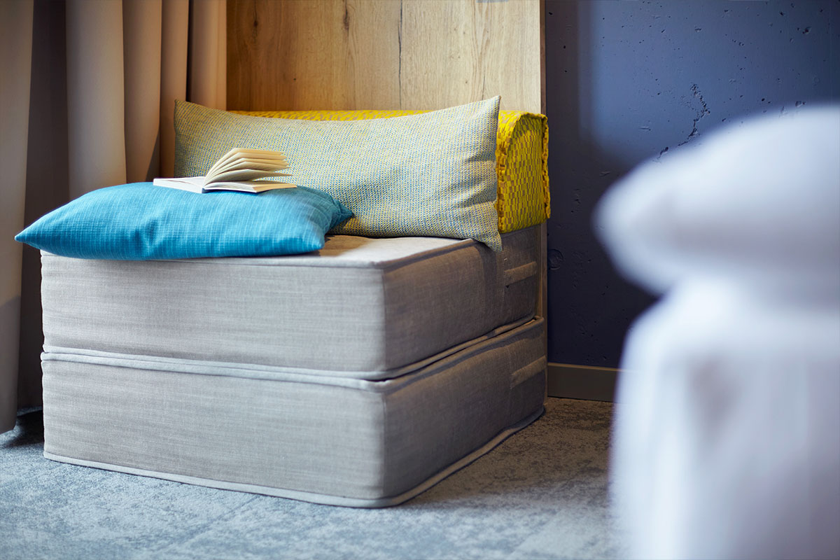 Detailaufnahme des Sessels mit Kissen und einem aufgeschlagenen Buch aus einem Doppelzimmer im arborea Marina Resort Neustadt.