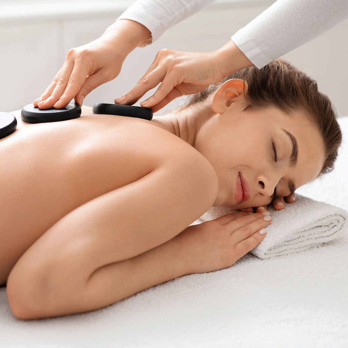 Eine Frau genießt die tiefgreifende Hot Stone Massage im SPARADISE des arborea Marina Resort Neustadt.